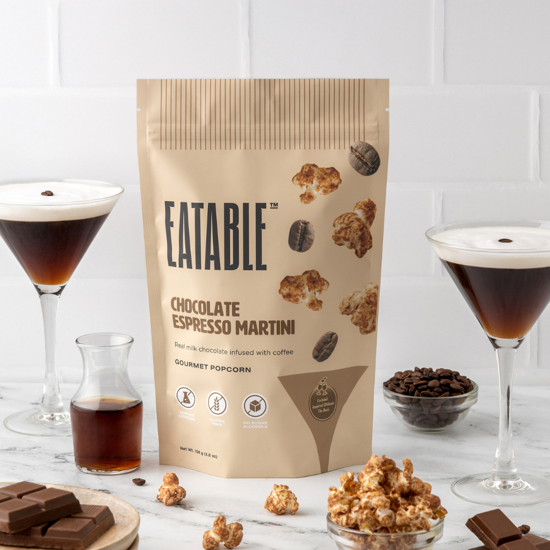 Eatable Chocolate Espresso Martini popcorn package with glasses of espresso and chocolate bars on a white background