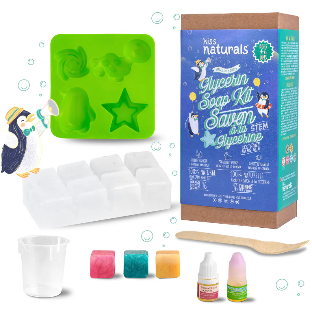 A cardboard box containing a Kiss Naturals Glycerin Soap Kit. The box is blue and white with the product name and a colorful illustration of penguins. It states that the kit is 100% natural, made in Canada, and suitable for ages 6 and up.