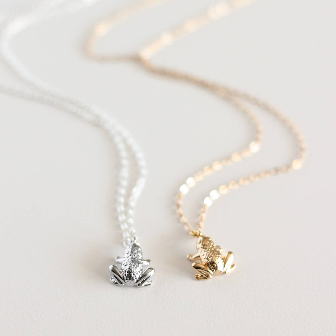 Two necklaces with frog pendants on a light background