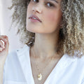 A gold necklace with a citrine stone pendant. The pendant also has the word "JOY" engraved on it. The necklace is displayed on a yellow card with the month "November" and the brand name "Foxy Originals."