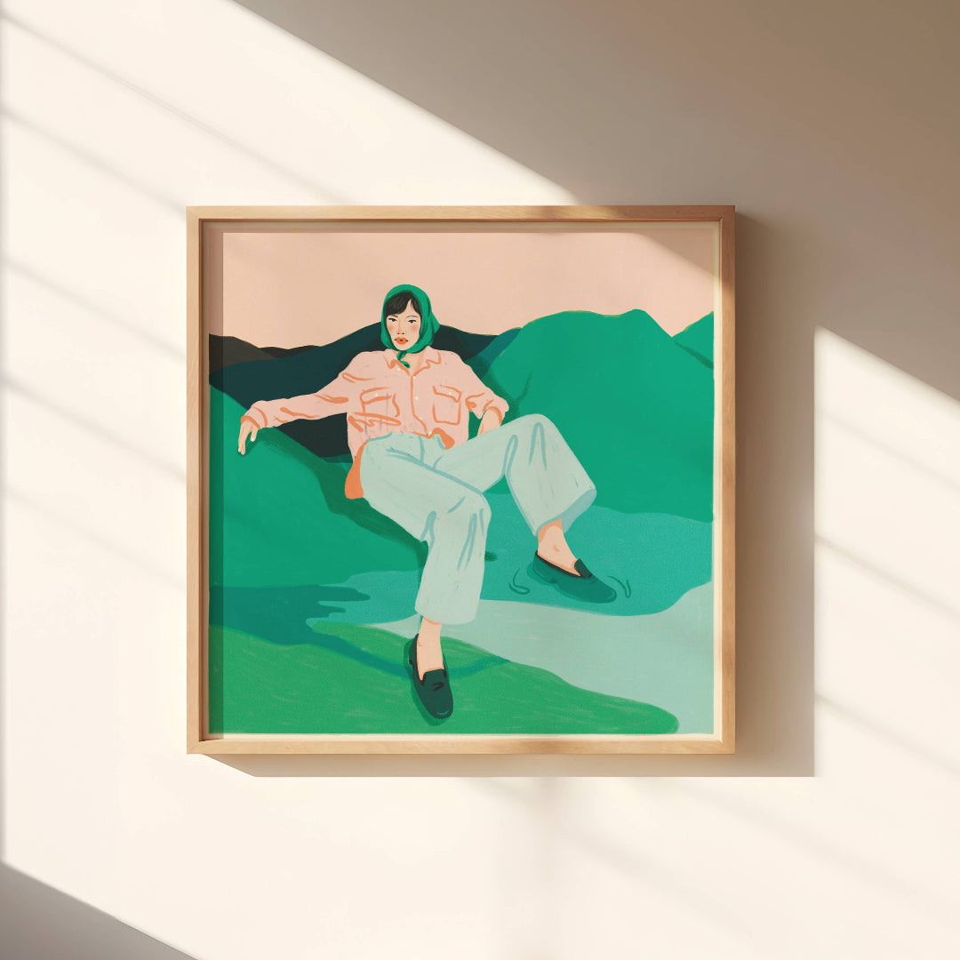 Framed artwork of a person sitting on a green landscape with a beige wall background