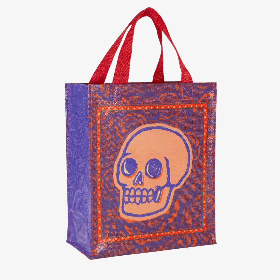 A reusable tote bag with a skull and roses design. The bag is purple with a large orange skull in the center. The skull is surrounded by red roses and has a black outline. The bag has red handles.