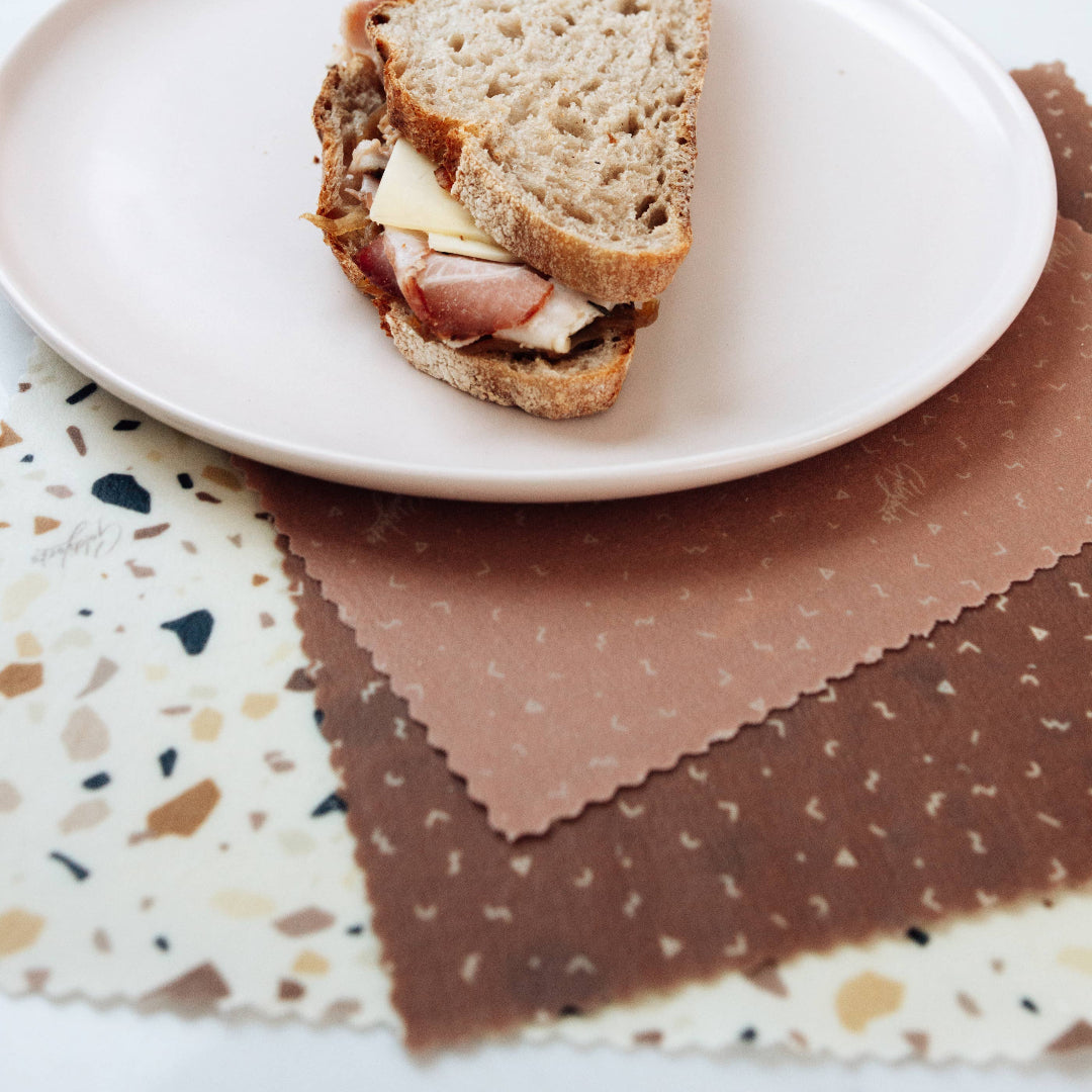 Half-eaten sandwich on a white plate with a brown napkin underneath
