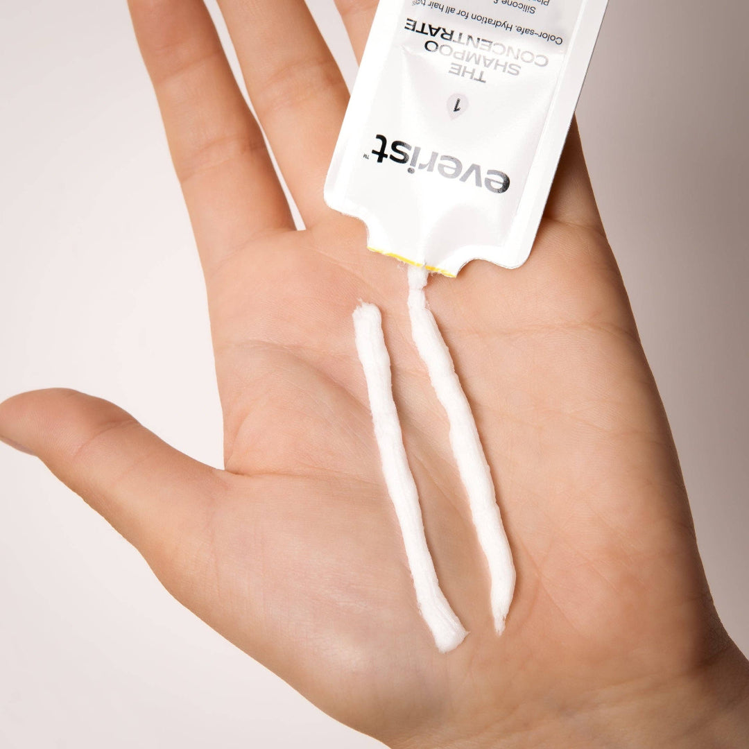 Hand holding a cotton swab with 'everist' packaging against a neutral background