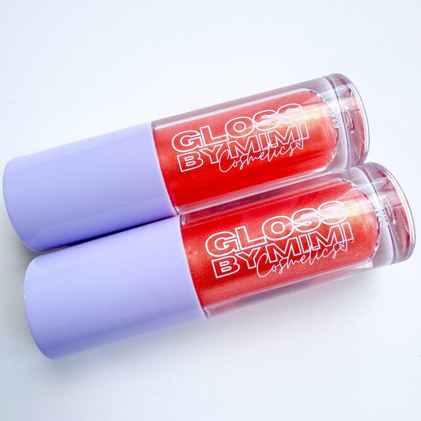 Two tubes of GLOSS by MIMI Winona Peach Lip Gloss with lavender caps and vibrant red shimmer gloss inside, perfect for showcasing a limited-edition peach-scented cosmetic.